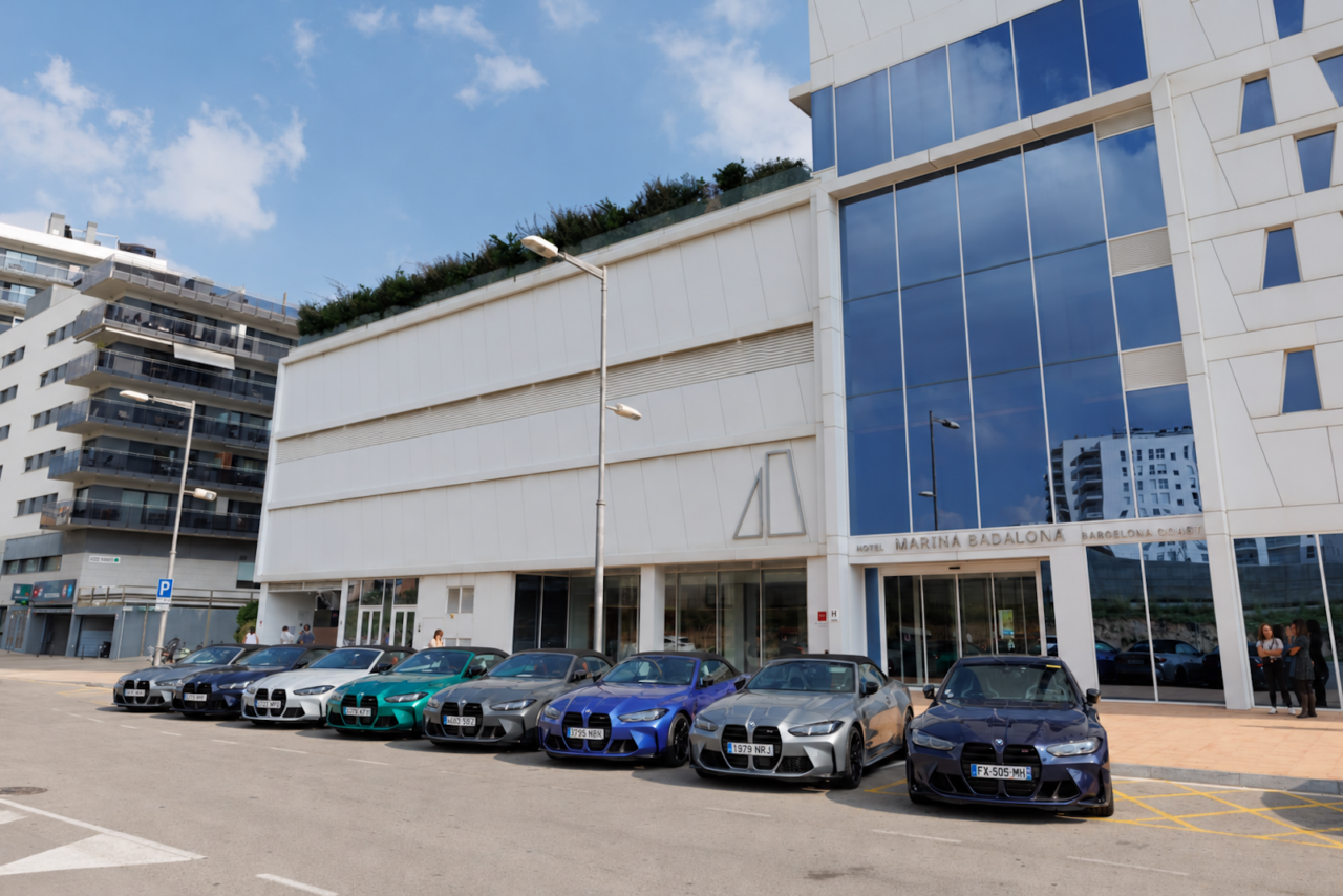 Sept BMW M3 et M4 de couleurs différentes alignées devant un bâtiment lors de la présentation Michelin