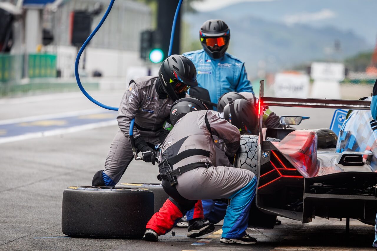 Arrêt aux stands d’une voiture d’endurance, mécaniciens changeant les pneus Michelin