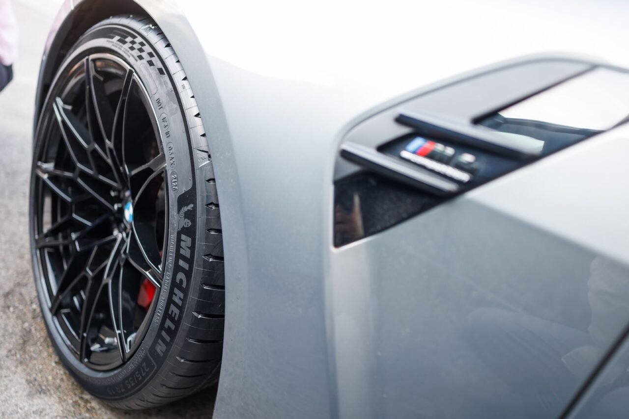 Pneu Michelin monté sur une BMW M grise, badge M visible sur l’aile